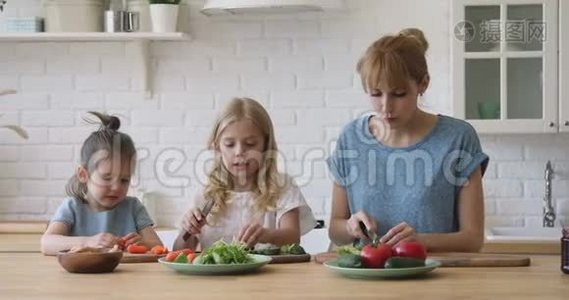 快乐的年轻妈妈教有趣可爱的小女儿准备食物。视频