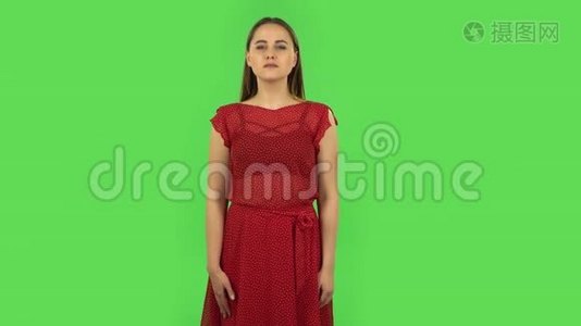 穿着红色衣服的温柔女孩把手掌放在一起，要求一些东西。 绿色屏幕视频