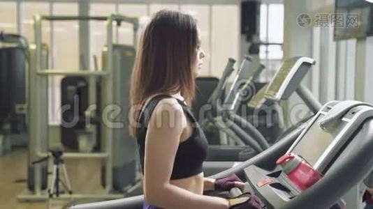 健身妇女在健身房跑步机上做有氧训练。 健身中心的运动女孩使用跑步机视频