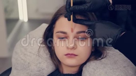 专业主眉妇女做脱毛与蜡眉对客户在美容院。视频