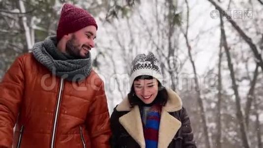 一对相爱的年轻夫妇在下雪的时候在公园里散步。男人和女友手牵手在冬日赏雪视频