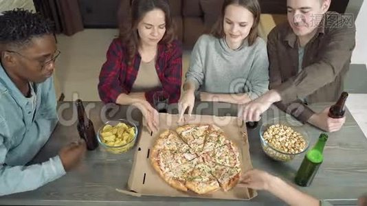 快乐的多民族朋友在家的客厅里喝啤酒，吃披萨，一起玩视频