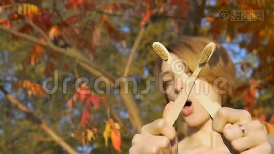 金黄短发的小女孩，在秋天阳光明媚的天气里，拿着一把竹制牙刷在户外视频