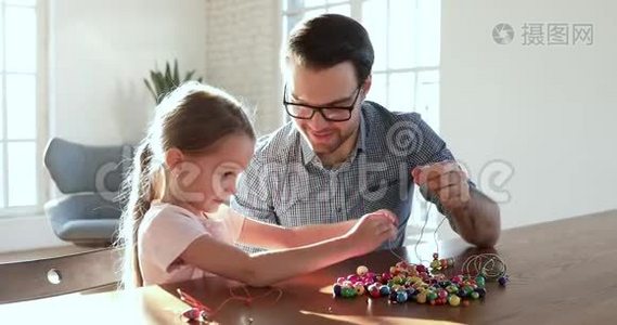 可爱的父亲帮助小女儿串珠项链视频