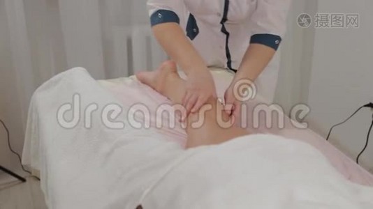 女按摩师在一个年轻女孩的小腿肌肉上做按摩。视频