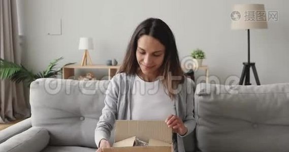 惊讶的年轻女子打开纸板箱与互联网商店的订单。视频