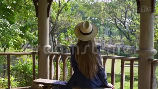 长发女子坐在夏季热带公园的长椅上视频