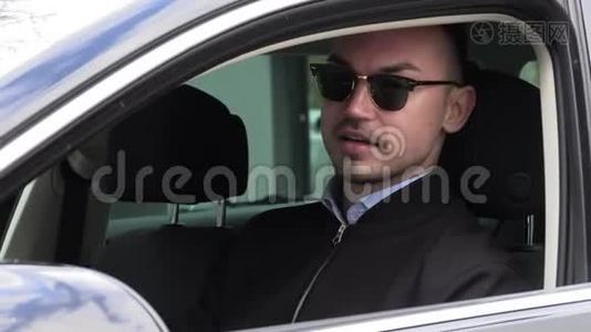 年轻时尚的男人戴着黑色太阳镜开车。视频