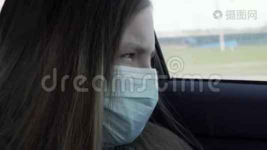 隔离概念。 戴口罩的恶心的小女孩坐在汽车后座上。 戴防护口罩的伤心女孩视频