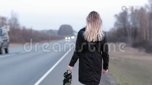 一个走在公路边上的女孩手里拿着一个黑色的防毒面具视频