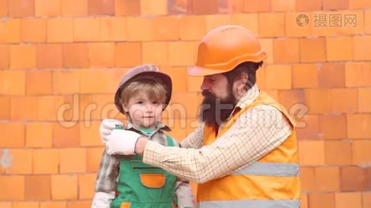 儿子和父亲放一块砖来建一堵墙。 男孩扮演建筑工或修理工。 父亲和孩子在家一起帮忙视频