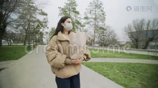 戴防护面具的年轻女子在冠状病毒流行期间步行携带购物袋视频