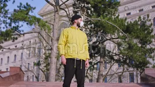 穿着一件黄色夹克，一个人站在空街中央的摄像机前，穿着隔离衣视频
