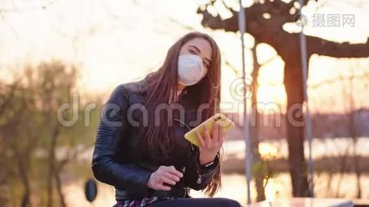 美丽的女性独自坐在公园里，她用手机打电话，她戴着保护面具，以保护视频