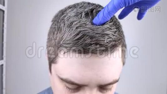 医生戴蓝色医用手套检查一个年轻人的白发。 青少年早期染发的概念视频