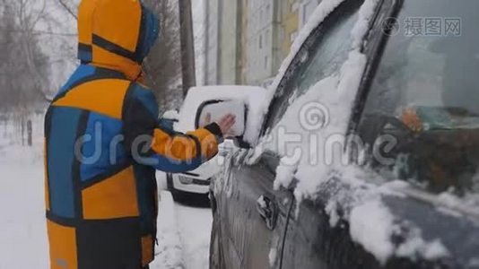 清理汽车侧窗积雪.. 一个孩子在雪地上清洗后视镜。 一个孩子`手清洁视频