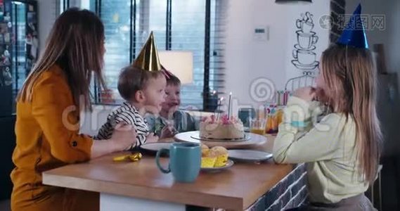 美丽快乐的白种人母亲帮助可爱的儿子在生日蛋糕上吹生日蛋糕与孩子和五彩纸屑慢动作。视频