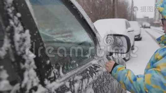 清理汽车侧窗积雪.. 一个孩子在雪地上清洗后视镜。 一个孩子`手清洁视频