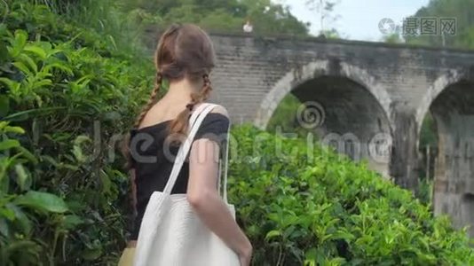 穿着黑色T恤的漂亮女孩沿着绿色种植园散步视频