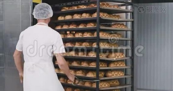 烘焙面包装入工业烤箱的过程中，烘焙工人在他旁边的大架子上装载食物视频
