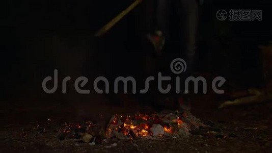 一个男孩在晚上拿着木头和从篝火中散发火花的不规则镜头视频