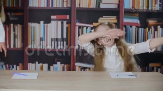 可爱的快乐嬉戏的女学生在图书馆的书桌前跳舞视频