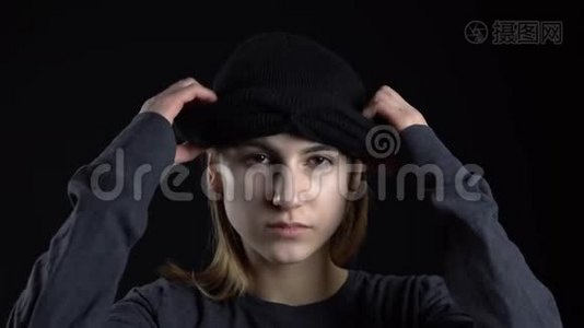 一个年轻的女人正在戴上巴拉克拉瓦面具。 黑色背景特写上的土匪。视频