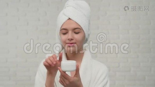 女人用毛巾把奶油涂在脸上。视频