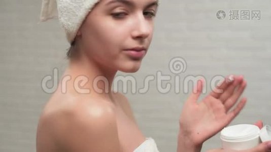 女人拿毛巾把奶油放在肩膀上。视频