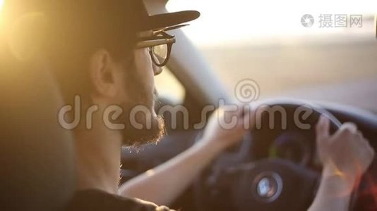 特写小胡子男驾驶汽车，具有日落的阳光效果..视频