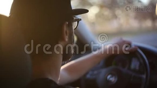 特写小胡子男驾驶汽车，具有日落的阳光效果..视频