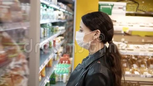 超市里戴着医用口罩的漂亮黑发年轻女子。大流行。选择产品视频