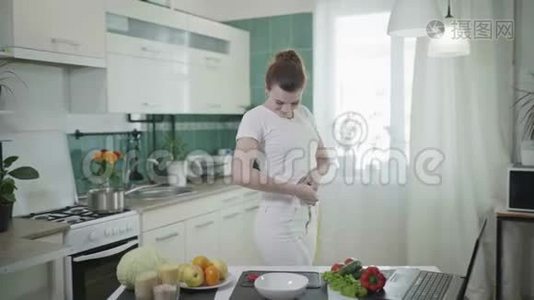 快乐的女人在成功的饮食后，用厘米的带子测量她的腰部，然后他用苹果夹胡椒视频