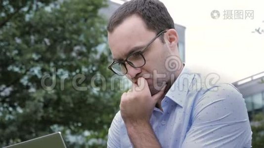 英俊的年轻商人用笔记本电脑坐着思考和思考。视频