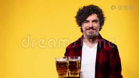 圣帕特里克节。 年轻的啤酒节男子提供大啤酒杯与饮料隔离在黄色背景。视频