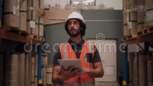 与大型配送用品之间的数字平板电脑行走清单相比，仓库中的男性工人视频