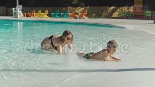 妈妈和她的小儿子在游泳池里玩视频