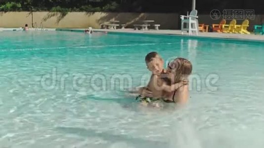 妈妈和她的小儿子在游泳池里玩视频