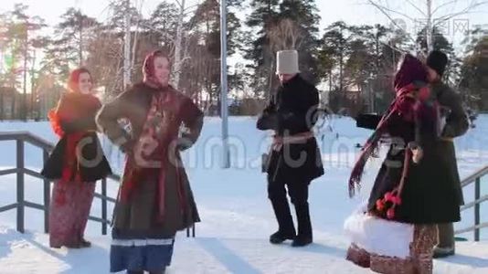 俄罗斯民间-穿着鲜艳围巾的女人和男人在冬季公园的楼梯上跳舞视频