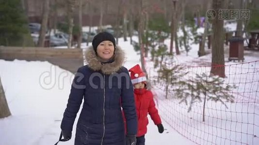一个年轻的女人和她的小儿子在一个山区度假活动公园玩油管。 寒假概念视频