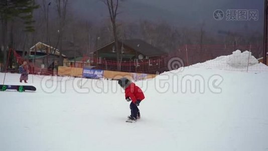 年轻人滑雪板教练教小男孩如何骑滑雪板。 冬季活动概念。 慢镜头视频