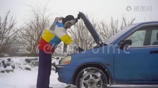 冬天，下着雪。 路上的人汽车出毛病了. 他正试图找出引擎的问题视频