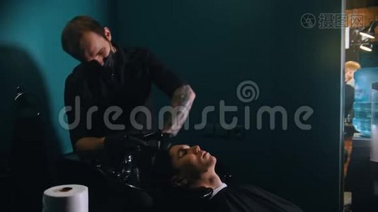 戴着纹身的男理发师给他的客户洗头视频