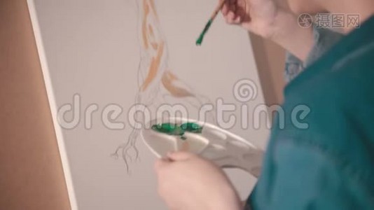 一位金发短发的年轻女子在艺术工作室里用绿色画树上枝视频