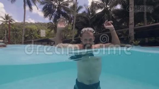 在热带小岛度假的时候，大胡子的年轻快乐男子正在游泳池里泼水。视频