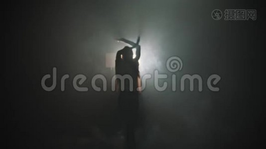 一个年轻女子的剪影，她的手在明亮的灯光背景下跳舞-走出黑暗视频