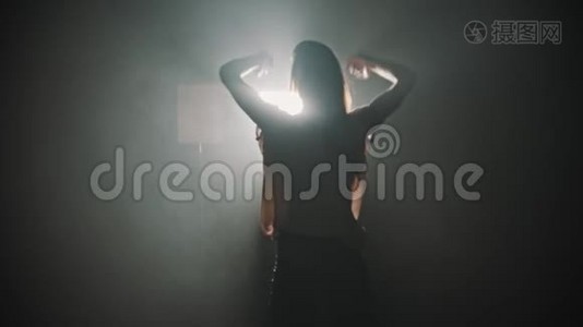 一个年轻女子的剪影，双手放在明亮灯光的背景上跳舞视频