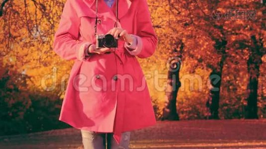 秋天公园里带照相机的时髦女人。穿着红色斗篷的时髦年轻女子视频
