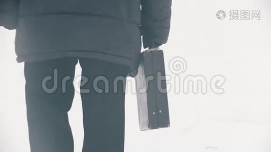 一个穿着羽绒服的老人带着袋子在雪地公园散步视频