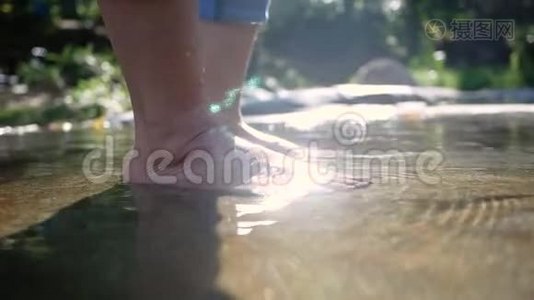 赤着脚的年轻女子在水流缓慢的溪流中溅起水花，踢着腿。 女士们享受假期视频